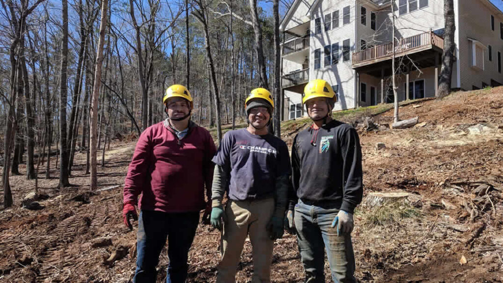 Three construction workers wearing helmets near house